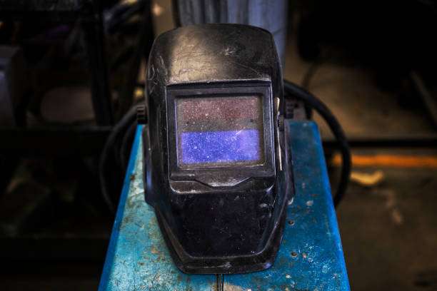 Close-up of a weathered black welding helmet with a blue tinted visor.