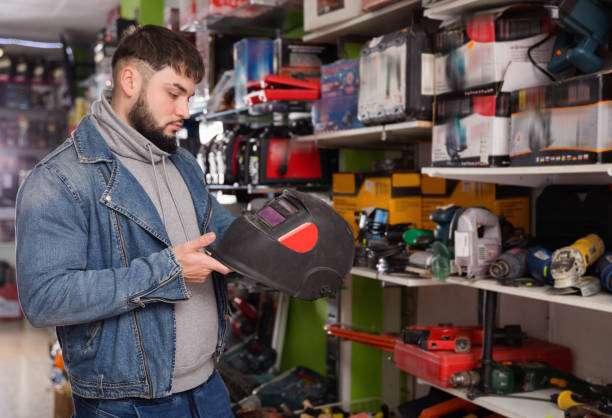 Man examining welding helmet in hardware store.