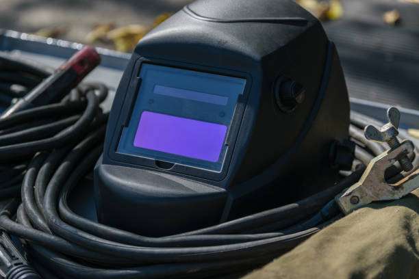 Black welding helmet with cables and clamp.