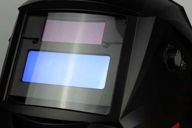 Close-up of a black auto-darkening welding helmet with active blue and purple lenses.